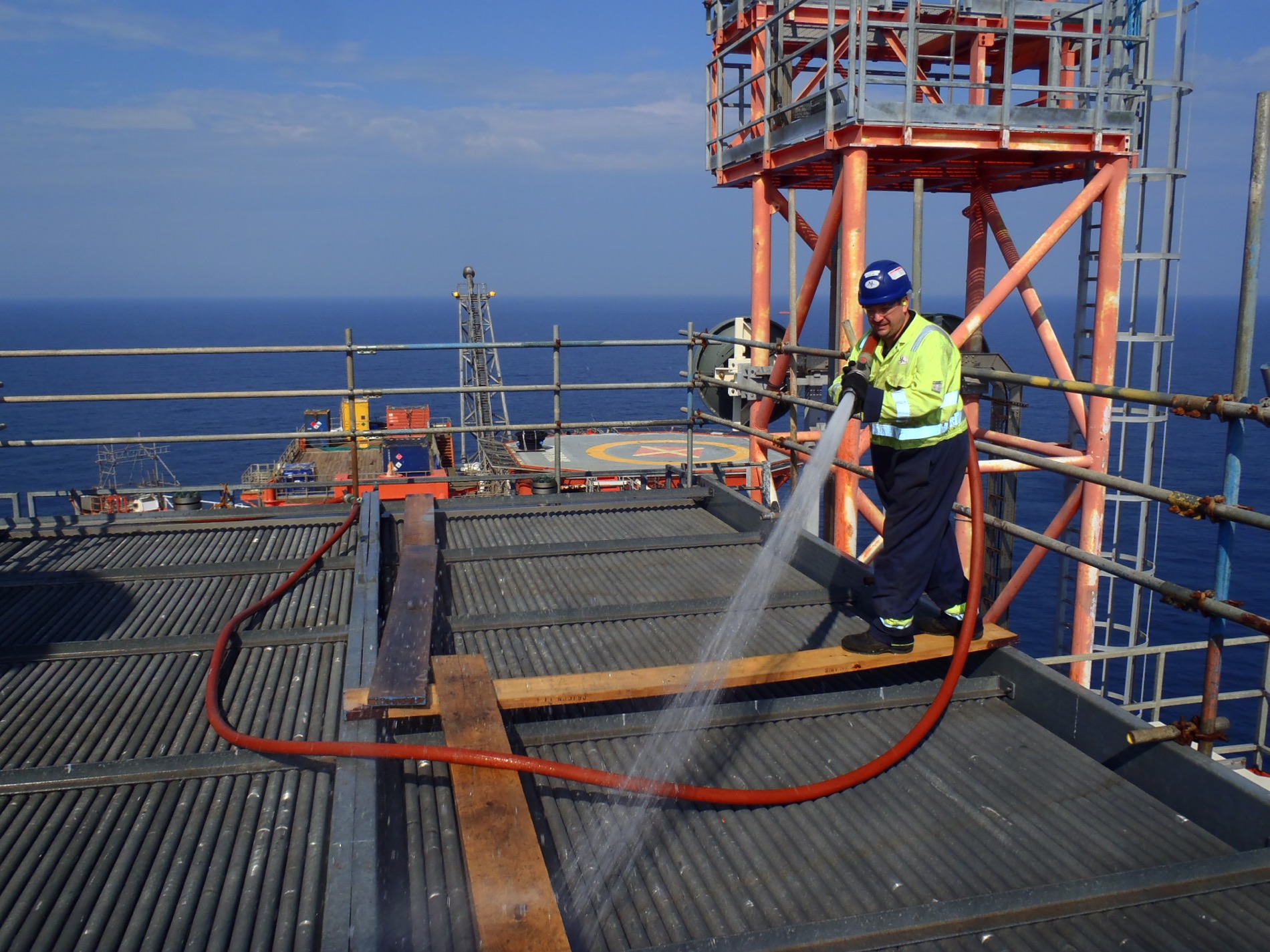 Technician cleaning an air cooled heat exchanger finned bundle on an offshore industrial installation